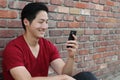 Portrait of a cool guy sitting on sidewalk looking at mobile phone with copy space Royalty Free Stock Photo