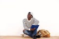 Cool male skateboarder sitting by a wall with book