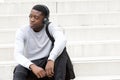 Cool young african american man sitting on steps and listening to music with headphones Royalty Free Stock Photo