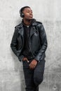 Cool young black man in leather jacket listening to music with headphones Royalty Free Stock Photo