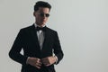 Portrait of cool young groom looking away and adjusting black tuxedo Royalty Free Stock Photo