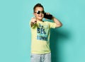 Portrait of a cool young teen guy talking on a mobile phone in summer style clothes in sunglasses, on a blue background. Royalty Free Stock Photo