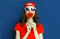 Portrait cool young woman with heart shaped red lollipop blowing red lips sending sweet air kiss wearing baseball cap, sunglasses Royalty Free Stock Photo