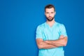 Portrait with copy space, empty place of virile harsh man with stubble in blue lab uniform, having his arms crossed Royalty Free Stock Photo