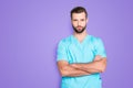 Portrait with copy space, empty place of virile harsh man with stubble in blue lab uniform, having his arms crossed Royalty Free Stock Photo