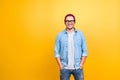 Portrait with copy space of smiling, happy guy in jeans wear, glasses, red cap holding hands in pocket, looking at camera over ye Royalty Free Stock Photo