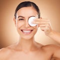 Portrait, cotton pad and woman with skincare, dermatology and happiness against a brown studio background. Face cleaning