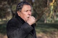 Portrait of a coughing senior man outdoors, looking down Royalty Free Stock Photo