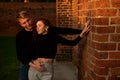 Romantic couple young beautiful sensual redhead woman and tall handsome blonde man posing in sunset sunlight on red Royalty Free Stock Photo