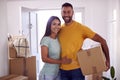 Portrait Of Couple Carrying Boxes Through Front Door Of New Home On Moving Day