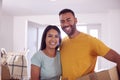 Portrait Of Couple Carrying Boxes Through Front Door Of New Home On Moving Day