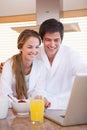 Portrait of a couple having breakfast while using a notebook Royalty Free Stock Photo