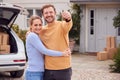 Portrait Of Couple Holding Keys Outside New Home On Moving Day Unloading Boxes From Car Royalty Free Stock Photo