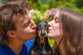 Couple in love kissing dog on walk in park, family idyll, threesome date