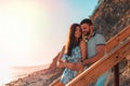 Portrait of a couple of lovers embrace standing on the stairs and pose against the background of the sea and sunset. The concept