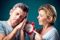A portrait of couple in the morning. Woman holding alarm clock, while man sleeping. People, relationships and emotions concept Royalty Free Stock Photo