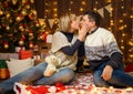 Portrait of a couple in New Year decoration. They kiss and have fun. Festive lights, gifts and a Christmas tree decorated with Royalty Free Stock Photo