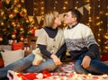 Portrait of a couple in New Year decoration. They kiss and have fun. Festive lights, gifts and a Christmas tree decorated with Royalty Free Stock Photo