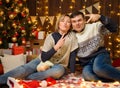 Portrait of a couple in New Year decoration. They pose and have fun. Festive lights, gifts and a Christmas tree decorated with Royalty Free Stock Photo