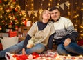Portrait of a couple in New Year decoration. They pose and have fun. Festive lights, gifts and a Christmas tree decorated with Royalty Free Stock Photo