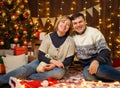 Portrait of a couple in New Year decoration. They pose and have fun. Festive lights, gifts and a Christmas tree decorated with Royalty Free Stock Photo