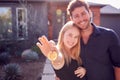 Portrait Of Couple With Pregnant Wife Standing Outdoors In Front Of New Home Holding Keys