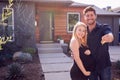 Portrait Of Couple With Pregnant Wife Standing Outdoors In Front Of New Home Holding Keys