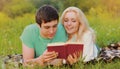 Portrait of couple reading a book together lying on the grass in park Royalty Free Stock Photo