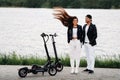 Portrait of a couple sitting near electric scooters, enjoying time in nature together, Two lovers on electric scooters.People on