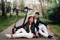 Portrait of a couple sitting near electric scooters, enjoying time in nature together, Two lovers on electric scooters.People on