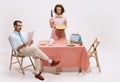 Portrait of couple sitting at the table, having breakfast on white background. Woman with knife. Movie remake