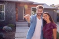 Portrait Of Couple Standing Outdoors In Front Of House With For Sale Sign In Garden Holding Keys Royalty Free Stock Photo