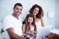 Portrait of couple using laptop with their daughter on bed Royalty Free Stock Photo