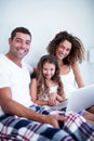 Portrait of couple using laptop with their daughter on bed Royalty Free Stock Photo