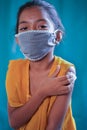 Portrait of covid vaccinated young gril kid with medical mask looking camera by holding arm - concept of coronavirus vaccination Royalty Free Stock Photo