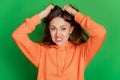 Portrait of crazy angry annoyed lady tear hair on green background