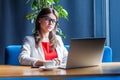 Portrait of crazy beautiful stylish brunette young woman in glasses sitting and looking at laptop display with crossed eyes funny