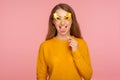 Portrait of crazy funny joyful ginger girl in casual sweater wearing fake paper eyeglasses and sticking out tongue, making faces Royalty Free Stock Photo