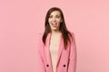 Portrait of crazy funny loony young woman in jacket with beveled eyes showing tongue on pastel pink wall