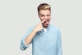 Portrait of crazy handsome young man in light blue shirt standing, drilling his nose, winking, tongue out and looking at camera Royalty Free Stock Photo