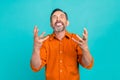 Portrait of crazy mad furious man with gray beard dressed orange shirt clenching teeth in anger isolated on turquoise