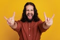 Portrait of crazy rock hipster harsh funky guy show two horns signs on yellow background