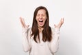 Portrait of crazy screaming young woman in light clothes keeping eyes closed spreading hands isolated on white wall