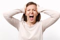 Portrait of crazy weird screaming young woman in light clothes putting hands on head isolated on white wall background