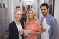 Portrait of creative business people holding digital tablets while standing in corridor Royalty Free Stock Photo