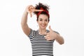 Portrait of creative young woman in headband, picturing moment, looking through hand frames gesture and smiling