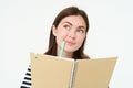 Portrait of creative young woman, looking thoughtful, holding pen and notebook, writing in her planner, thinking while Royalty Free Stock Photo