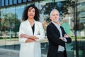 Portrait of crossed arms business people looking at camera with successful expression. Couple of multiracial proud Royalty Free Stock Photo