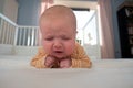 Portrait of crying baby girl lying alone on bed. Royalty Free Stock Photo