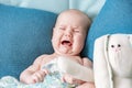 Portrait of a crying baby on a green bed in the bedroom. Child`s emotions Royalty Free Stock Photo